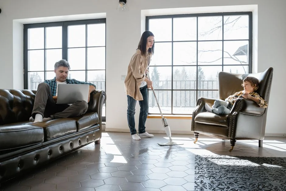 a-woman-in-a-green-shirt-and-black-gloves-vacuuming-a-gray-ottoman-5txz228u4eo