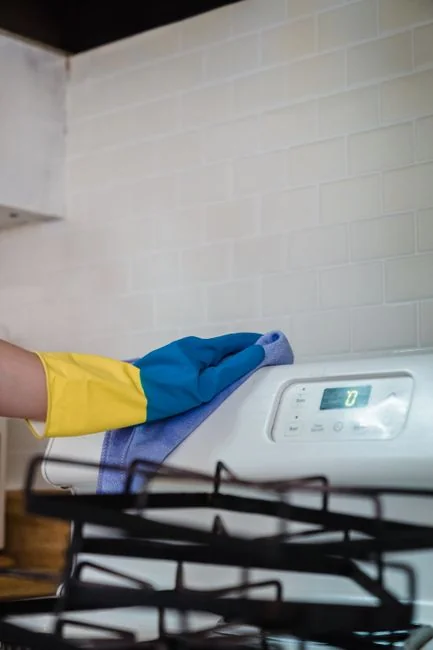 Anonymous male wearing yellow latex gloves and dark t shirt wiping mirror in bathroom with paper napkin